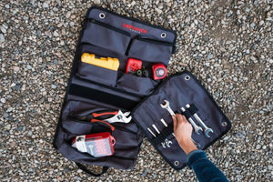 Open tool bag with various tools on a textured surface